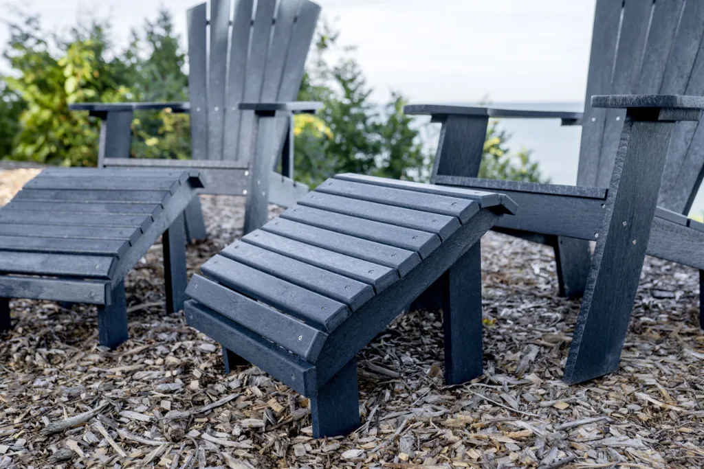 Navy Generations Premium Adirondack Footrest in front of two Adirondack chairs on the coast