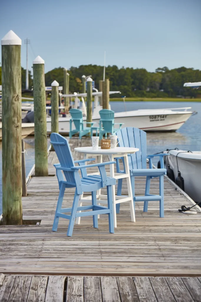 A white 32" Round Top Counter Table on a pier surrounded by two Addy chairs