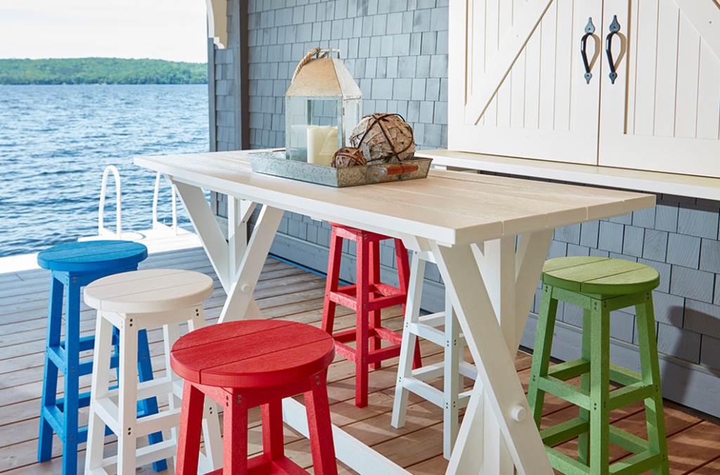 A Counter height table surrounded by red white and blue stools on a stunning beachfront porch