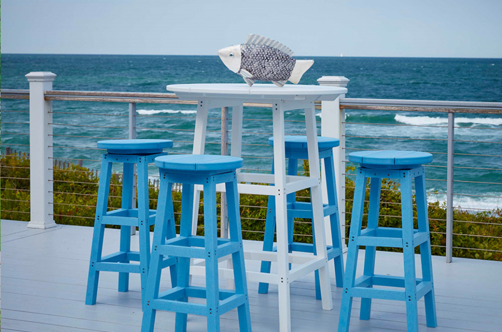 Three light blue stools surrounding a counter-height dining table on a beautiful coastal porch