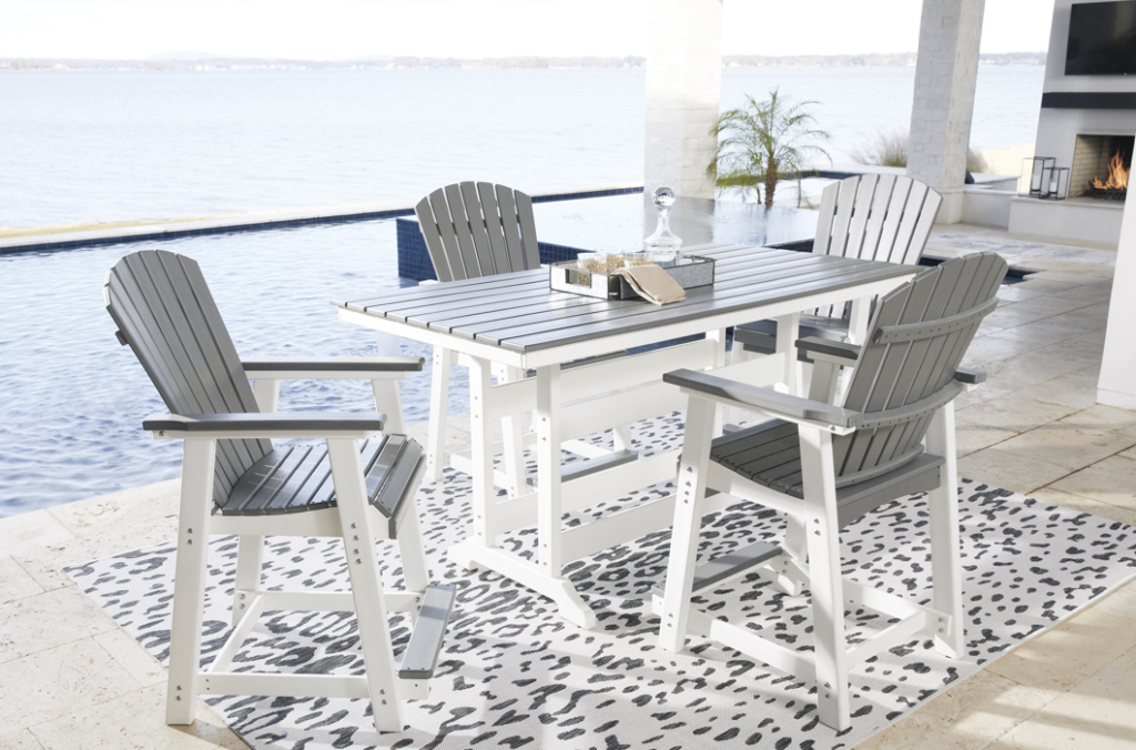 Four beautiful grey and white chairs surrounding a circular white table on a coastal porch