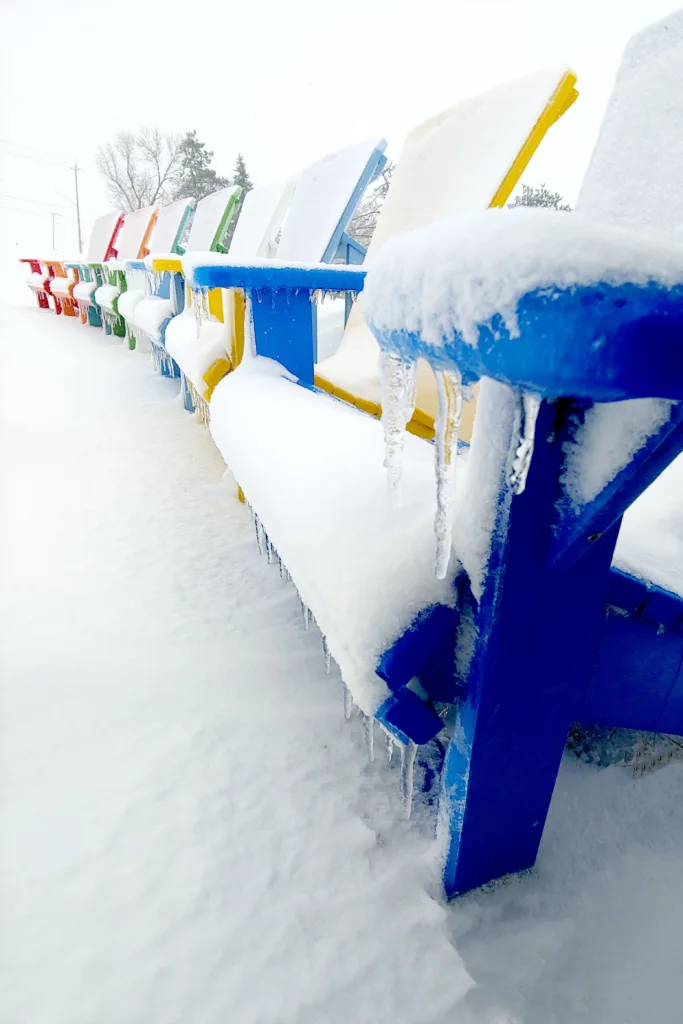 Generations Upright Adirondack Chairs lined up in a line, frozen over with snow in mid winter