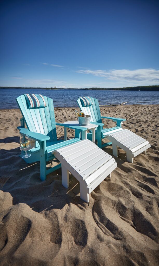 White Generations Addy Side Table Surrounded by two Adirondack chairs